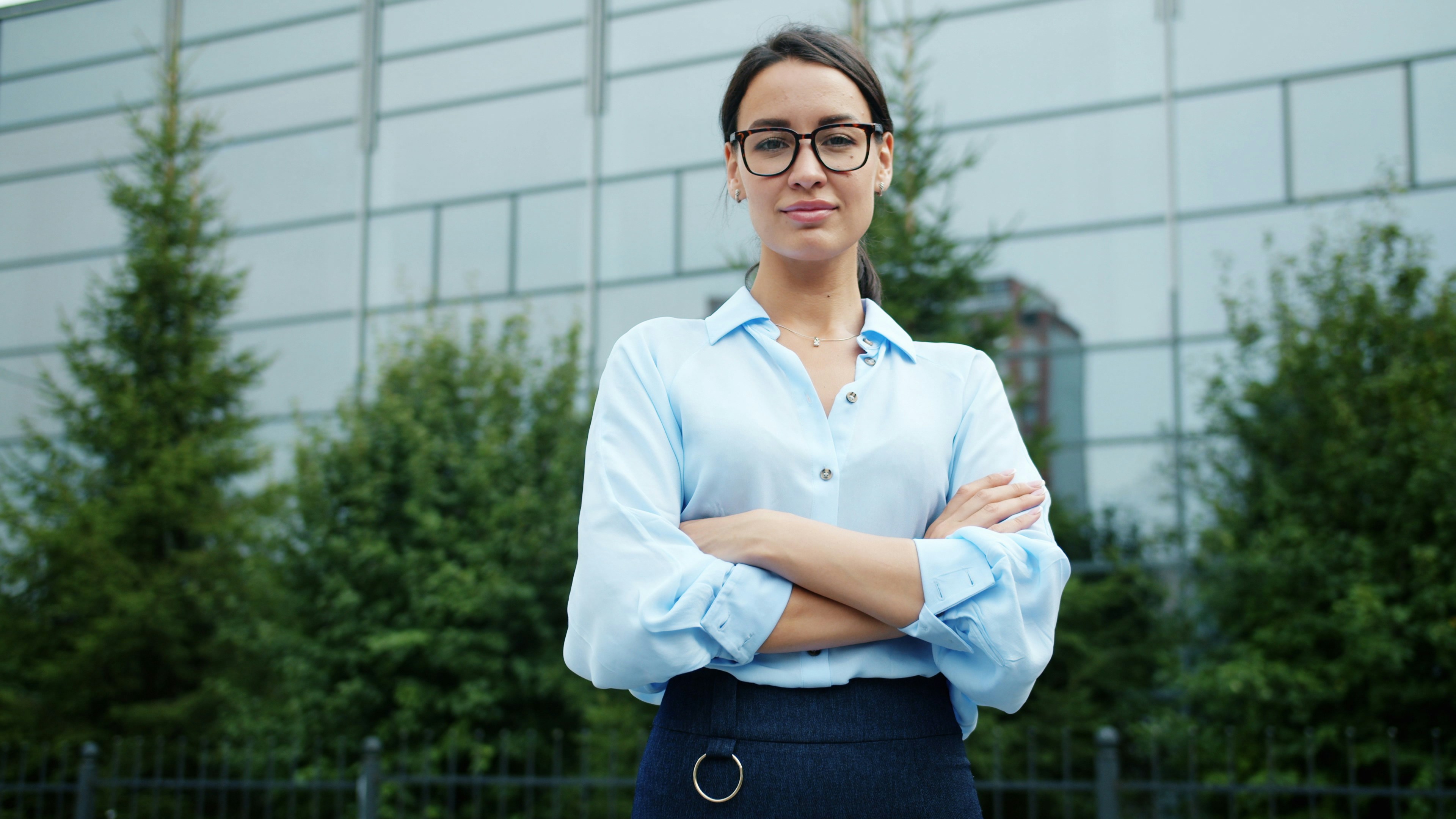 Accountant with arms crossed outside a modern glass office building